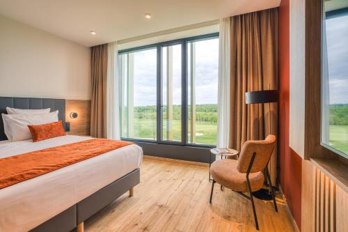 a hotel room with a bed and a large window at Bois d'Arlon Hotel & SPA in Arlon
