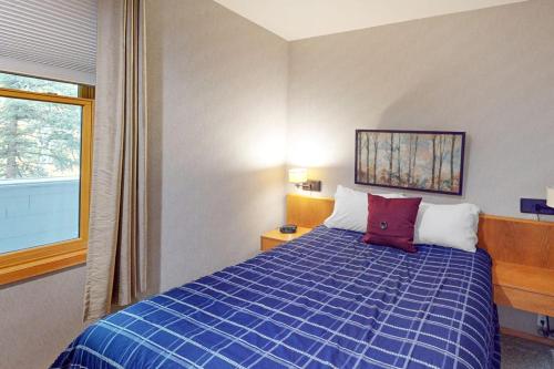 a bedroom with a blue bed and a window at River Bank Lodge 2924 in Keystone