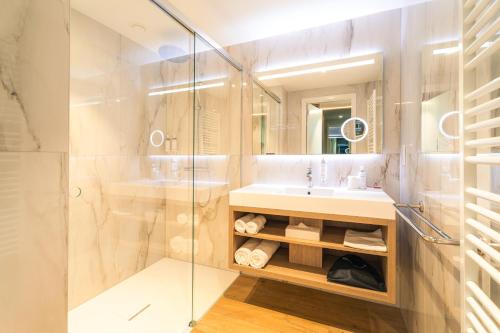 a bathroom with a sink and a glass shower at Bois d'Arlon Hotel & SPA in Arlon