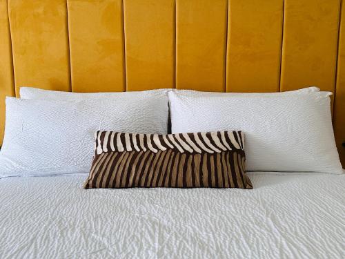 a bed with white sheets and a pillow on it at Hotel Ti' Pelican in Saint-Pierre