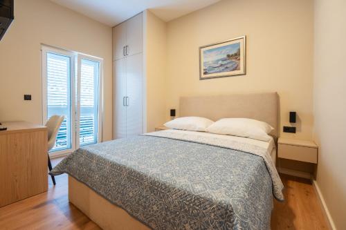 a bedroom with a large bed and two windows at Guest house AnĐela in Neum