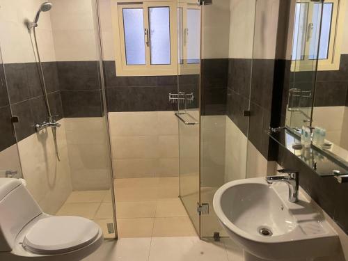 a bathroom with a toilet and a shower and a sink at Ruru Tower Luxury Apartment in Juffair
