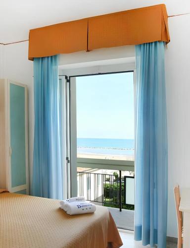 a bedroom with a bed and a large window at Hotel Dolores in Rimini