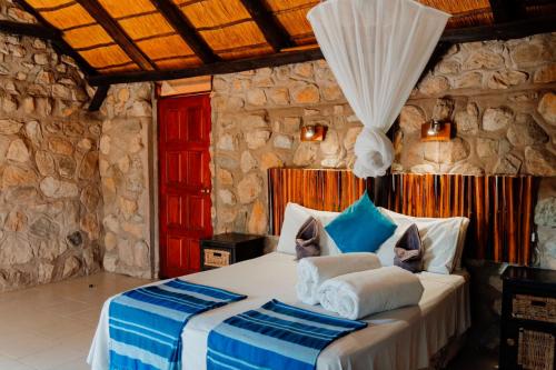 a bedroom with a bed in a stone wall at Kapika Waterfall Lodge in Epupa