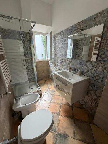 a bathroom with a toilet and a sink and a shower at Bouganville House in Nettuno