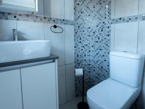 a bathroom with a white toilet and a sink at Oliverio Seaside Living in Sedgefield