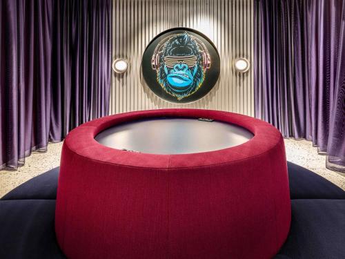 a room with a red table and a painting on the wall at ibis Styles Muenchen Perlach in Munich