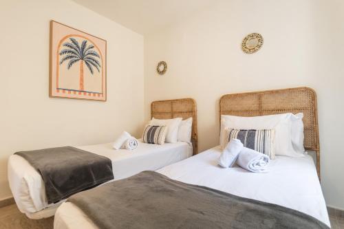 two beds in a room with a palm tree picture on the wall at Las Dunas by Ĥ in Isla del Moral