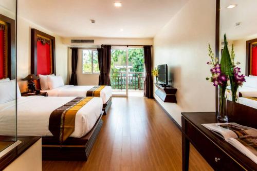 a hotel room with two beds and a television at Royal Heritage Pavilion, Jomtien in Jomtien Beach