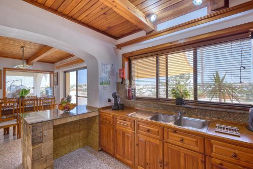 a kitchen with wooden cabinets and a large window at D View 4 You in Mellieħa
