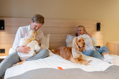 Ein Mann sitzt mit zwei Kindern und einem Hund auf einem Bett. in der Unterkunft Citybox Bergen City in Bergen