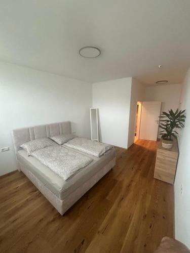 a white bedroom with a bed and a wooden floor at Nous Cafe & Restaurant in Krumnussbaum
