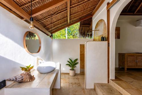 a bathroom with a sink and a mirror at Jala Villas Lances Right HTs Mentawai in Katiet
