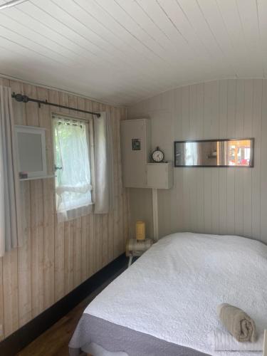 a bedroom with a white bed and a window at Le wagon roulotte in Thorigny-sur-Marne