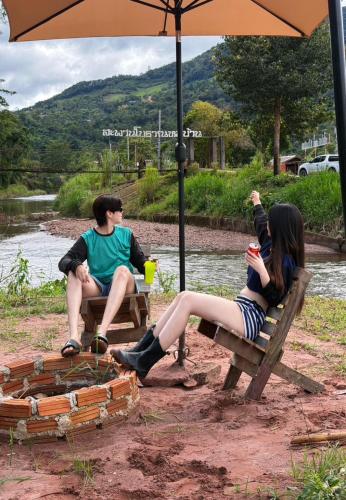 a group of three people sitting on benches under an umbrella at สะปันไลฟ์ in Ban Huai Ti