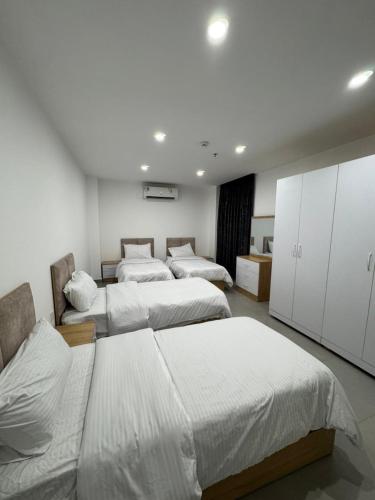 three beds in a room with white walls at Rami Grand Residence in Erbil