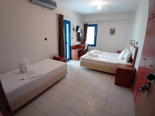 a hotel room with two beds and a bathroom at Hotel Eleni in Paralia Dionysiou