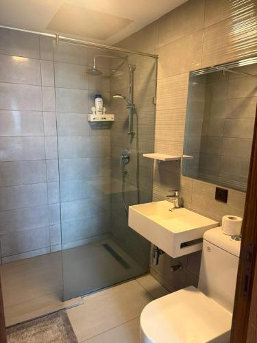 a bathroom with a shower and a sink and a toilet at QUATTRO-Sky Suites in Accra