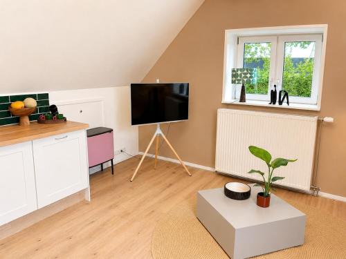 a living room with a flat screen tv and a table at Wonenmeteenknipoog Groningerweg 23D in Peize