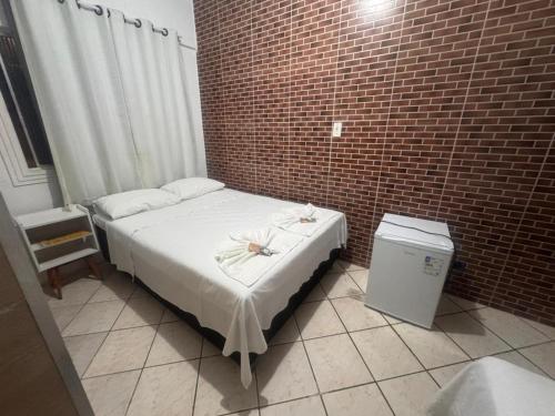 a small bedroom with a bed and a brick wall at Pousada Marúa Fortaleza in Fortaleza