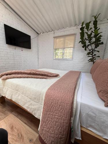 a bedroom with two beds and a flat screen tv at Cabaña entre Cafetales in Manizales