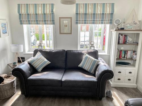 a black leather couch in a living room with windows at The Bay - The Bolthole in Reighton