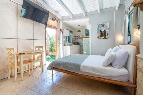 a bedroom with a bed and a table and a kitchen at בצל הדקל in Bet Leẖem HaGelilit