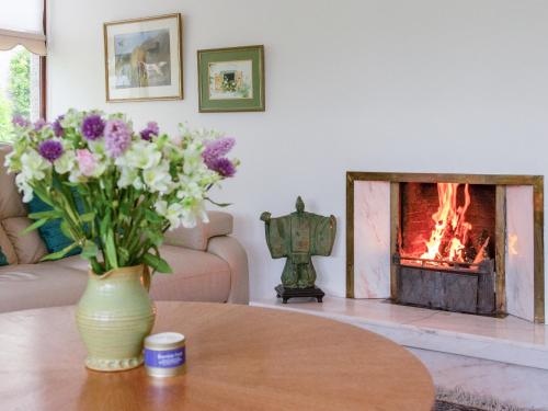 a vase of flowers on a table in a living room with a fireplace at Middle Lodge in Mintlaw
