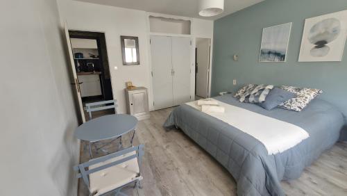 a bedroom with a bed and a table in it at la Villa des Fleurs in La Bourboule