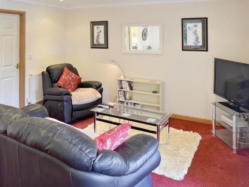 a living room with a leather couch and a tv at River Lodge in Polperro