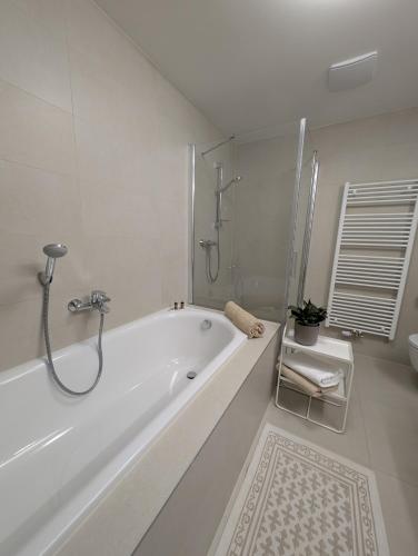 a white bathroom with a tub and a shower at Apartment VIEW 27 in Olomouc