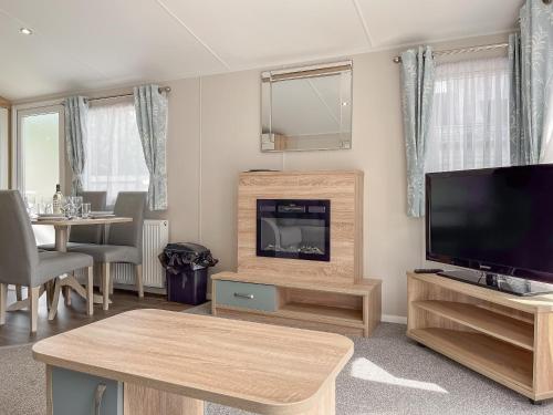 a living room with a flat screen tv and a table at Whispering Pines Spa - Uk50087 in Durham