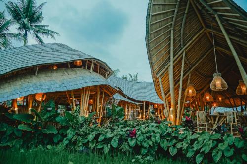 a building with a restaurant with tables and plants at Green Lander Ubud in Ubud