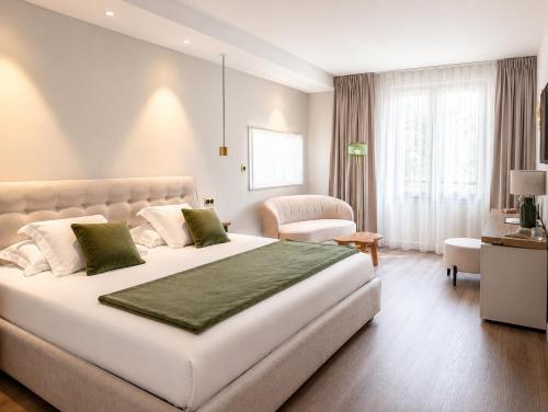 ein Schlafzimmer mit einem großen weißen Bett und einem Stuhl in der Unterkunft Le Dracy Hôtel et Spa in Dracy-le-Fort