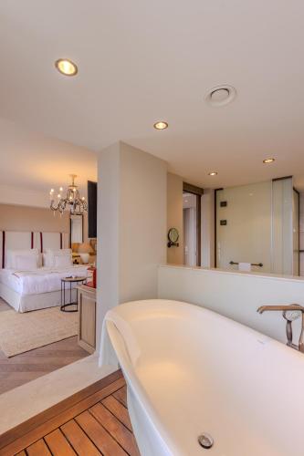a large bathroom with a tub and a bedroom at Allium Bodrum Resort & Spa in Yalıkavak