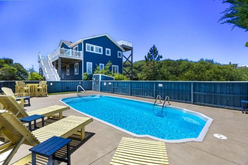 a swimming pool with chairs and a house at 1030 - La Ballena Cottage in Corolla
