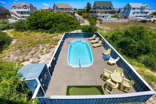 an overhead view of a swimming pool with chairs and tables at 1030 - La Ballena Cottage in Corolla