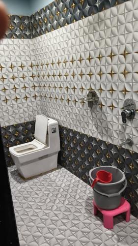 a bathroom with a toilet and a red stool at Hotel Diamond in Gwalior