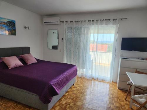 a bedroom with a purple bed and a television at Apartmani Kramar in Selce
