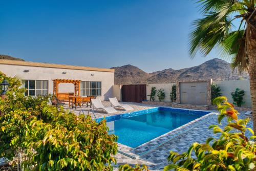 a house with a swimming pool with mountains in the background at 800 Mountains view in Fujairah