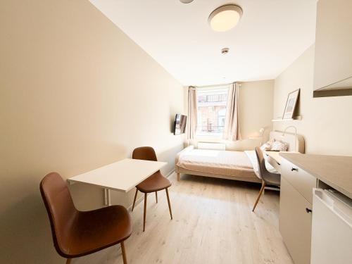 a small room with a bed and a table and chairs at Kongens Gate Rooms in Kristiansand