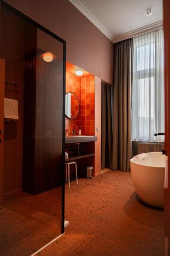 a bathroom with a large tub and a sink at Hotel Amfora in Poperinge
