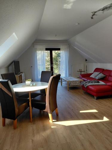 a living room with a table and a red couch at Ferienwohnung Knoll in Lähden