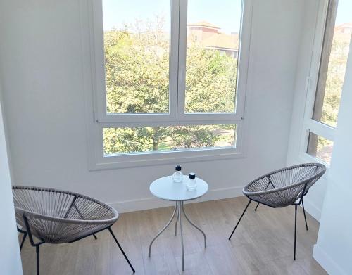 two chairs and a table in a room with two windows at Sand House Gorliz By Kima Gestión in Górliz-Elexalde