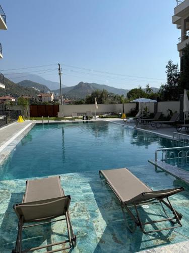 a swimming pool with two chaise lounge chairs next to it at Fethiye Serenity Suites in Fethiye