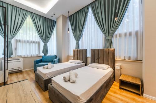 a bedroom with two beds and a blue chair at Palm Beachfront Suites by PS in Durrës