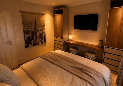 a bedroom with a bed and a tv on the wall at Erftlodges L2 in Bad Münstereifel