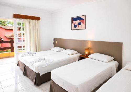 a hotel room with two beds and a window at Flat Incrível Amarilis dentro da Riviera São Lourenço - 2 Unidades disponíveis, Duplex 2 Quartos, Cozinha e Varanda ou Unidade tipo Estúdio sem Cozinha in Riviera de São Lourenço