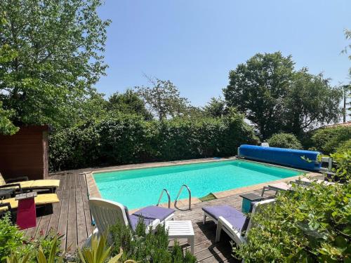 a swimming pool with chairs and a table and a pool at Maison d'Hôtes L'Escale Du Loup Blanc in Maringes