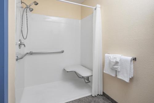 a bathroom with a shower with a chair and towels at Days Inn by Wyndham Waynesville NC in Waynesville